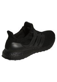 Chaussure de sport noire avec une tige en mesh texturé, un détail à trois bandes, et une semelle rembourrée et profilée portant l'inscription « ultra boost ».
