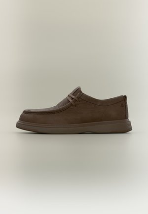 Καφέ δερμάτινο casual παπούτσι χωρίς κορδόνια με υφή στο πάνω μέρος και ελάχιστα κορδόνια, με φόντο απλό και φωτεινό, πλευρική όψη.
