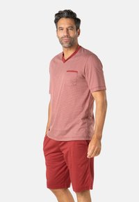 Chemise rouge à motifs à manches courtes avec encolure en V et poche poitrine, assortie à un short rouge uni. Les deux sont en tissu doux et léger.