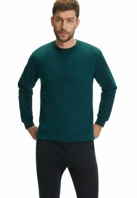 Felpa girocollo verde scuro realizzata in un tessuto testurizzato, con maniche lunghe e un sottile dettaglio del logo sul petto.