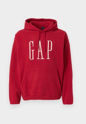 Sweat à capuche en polaire rouge avec une poche kangourou, capuche à cordon, et grand logo blanc "GAP" sur le devant. Texture douce et coupe décontractée.