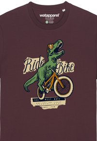 T-shirt en coton brun avec un dinosaure vert faisant du vélo, accompagné du texte "Fais du Vélo" et des accents en jaune et crème.