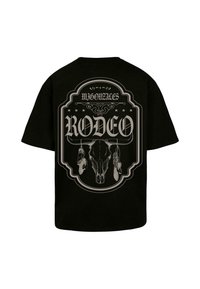 Svart T-skjorte med et stort grafisk trykk av et oksehode med fjær og ordet "RODEO" med fete bokstaver på baksiden.