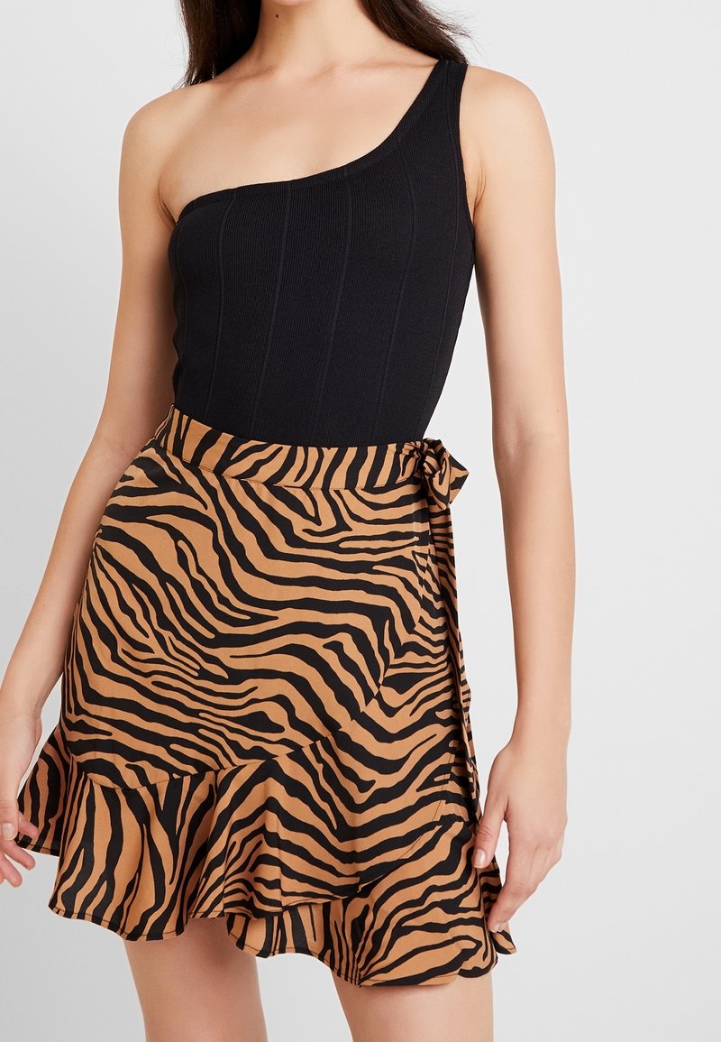 Body noir côtelé à une épaule, associé à une jupe portefeuille à rayures tigre marron et noire, avec un ourlet volanté et un lien sur le côté.