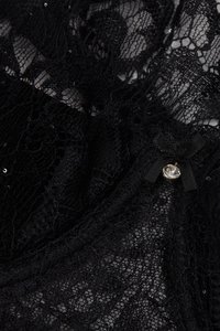 Tissu en dentelle noire avec un motif floral, orné d'un petit nœud noir et d'un accent en cristal. Conception texturée et finement détaillée.