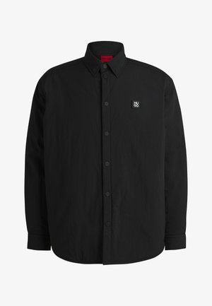 Black long-sleeve shirt with a button-down collar, subtle texture, and a small rectangular logo on the left chest. Black buttons and cuffs.