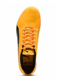 Zapato de fútbol Puma con una parte superior sintética de un brillante color naranja, lados negros en contraste, cordones naranjas y una plantilla impresa que dice "SIEMPRE. MÁS RÁPIDO."