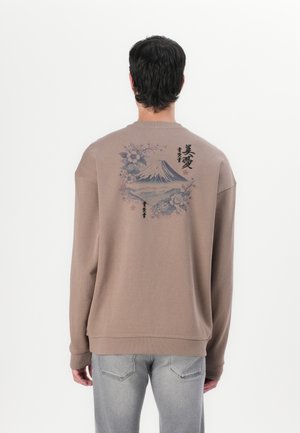 Brown sweatshirt with a loose fit, featuring a mountain graphic and floral designs on the back. Ribbed cuffs and hem details.