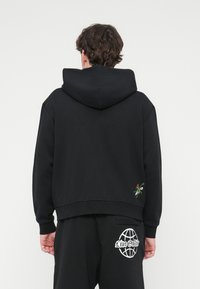 Μαύρο πουλόβερ με κουκούλα, με κεντητό λουλουδάτο σχέδιο στο κάτω μέρος και ριμπ τελείωμα. Μαλακό ύφασμα και άνετη εφαρμογή.