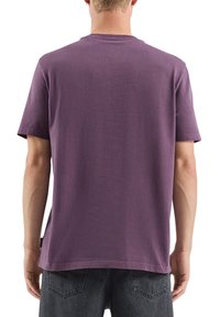 Fioletowy bawełniany T-shirt z okrągłym dekoltem, krótkimi rękawami i luźnym fasonem. Z tyłu gładki, bez widocznych logo czy wzorów.