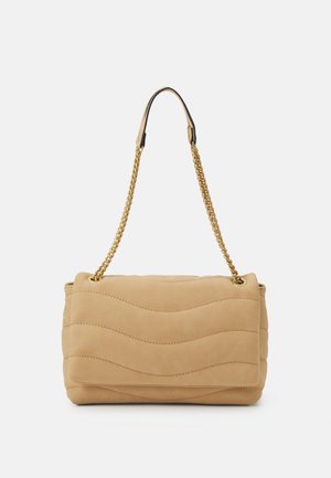 Beige gewatteerde handtas met golvende stiknaden en gouden kettingriem, afgebeeld tegen een effen lichte achtergrond.