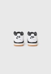 Sapatilhas brancas da Nike com recortes pretos, bico redondo, língua acolchoada e sola de borracha. Logotipo na parte do calcanhar e na área de atacadores.