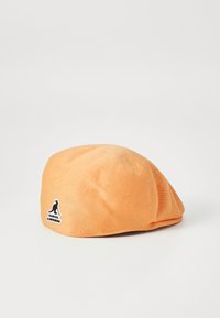 Beret tricotat portocalie cu o suprafață texturată. Prezintă o etichetă cu logo-ul Kangol închis pe lateral, formă rotundă și material moale.