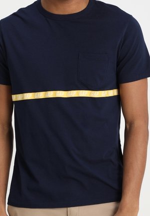 Navy blue cotton t-shirt with a yellow GAP branded stripe across the chest and a small left chest pocket. Short sleeves, crew neck design.