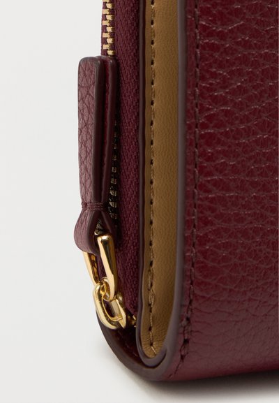 Bordeaux leren portemonnee met gouden hardware, een gestructureerde afwerking en een contrasterende tan voering met een ritsluiting.