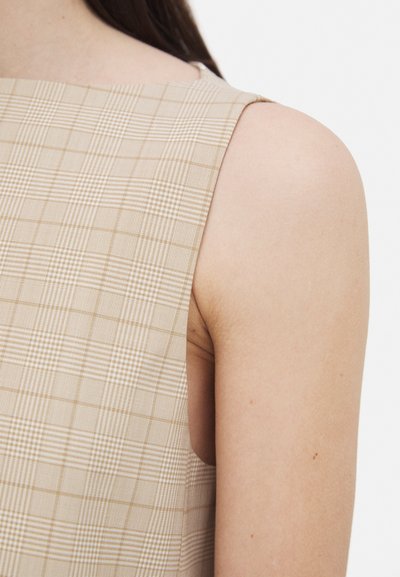 Beige karierter ärmelloser Top mit strukturiertem Design und dünnen, hellen Linien. Glatte Textur, mit freiliegenden Schultern und sauberen Kanten.
