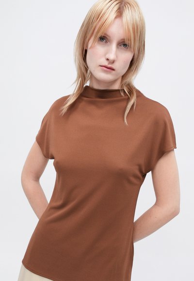 Top scurt maroniu cu mâneci scurte, cu un guler înalt, fabricat dintr-un material neted, cu o siluetă ajustată și un design minimalist.