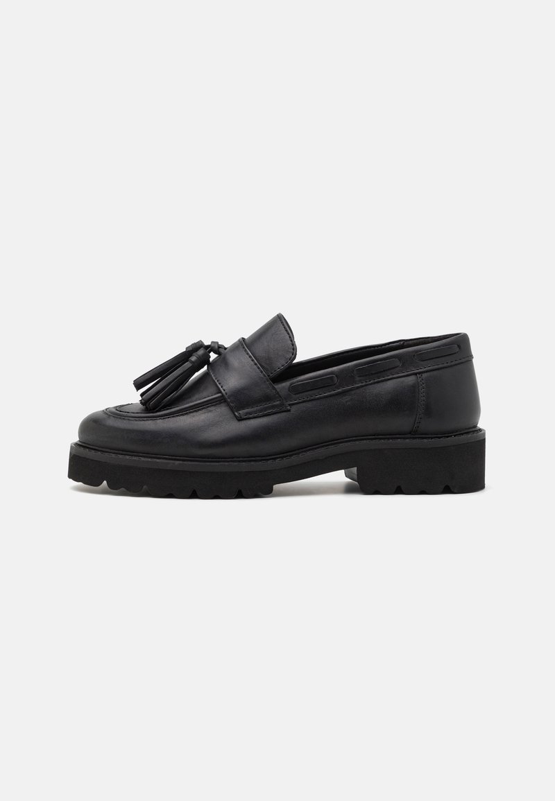 Svarta läderloafers med en platt, texturerad sula, dekorativa fransar framtill och en stilren, minimalistisk design.