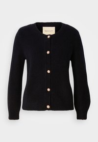 Tamsiai mėlynas megztas kardiganas su apvaliu iškirpimu, puošiamas auksiniais mygtukais su perlų akcentais priekyje ir ilgomis rankovėmis.