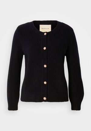 Marineblå strikket cardigan med rund hals, med gylne knapper og perleaccenter langs fronten og lange ermer.