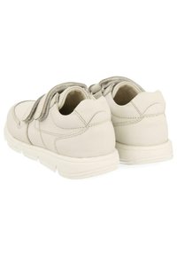 Zapatillas de cuero blanco con dos correas de velcro, forma redondeada, cuello acolchado y costura lateral texturizada. Suela de goma suave.
