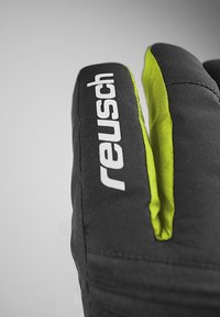 Svarta handskar med en framträdande vit "Reusch"-logotyp. Utsmyckade med klargrönt på fingertopparna, som visar en strukturerad tygdesign.