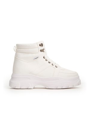 Zapatillas altas blancas de material sintético, con una suela de goma gruesa, parte frontal con cordones y adornos de metal plateado.