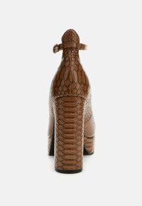 Chaussure à talons hauts en cuir serpent synthétique marron avec un talon épais, une sangle à la cheville et une surface texturée présentant un motif écaille.