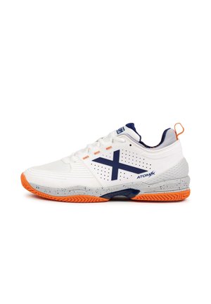 Zapatilla deportiva blanca con detalles en azul marino y suela naranja. Presenta paneles laterales perforados, talón texturizado y un diseño acolchado para un mejor rendimiento.