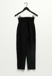 Pantalons noirs taille haute avec une ceinture nouée, présentant une coupe ample, un design plissé et une texture de tissu douce. Accrochés à un crochet noir.
