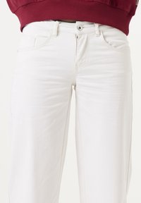 Witte denim broeken met een getailleerde taille, voorzakken en een ritssluiting. Halen textuur met minimale stikdetails.