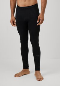 Leggings thermiques noirs avec une taille et un corps texturés, design ajusté, arborant le logo de The North Face près de la cheville.