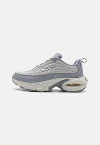 Nike Air Max teniska z zgornjim delom iz sivega mrežastega materiala, gladkimi sintetičnimi akcenti, zaobljenim oblikovanjem in vidnim zračnim blaženjem v podplatu.