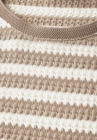 Strickoberteil in Beige mit weißen Streifen. Es hat ein strukturiertes Muster und einen runden, strukturierten Ausschnitt.