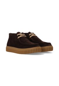 Braune Wildleder-Stiefeletten mit beigen Schnürsenkeln und kontrastierender Gummisohle. Mit gesteppten Details und runder Form.