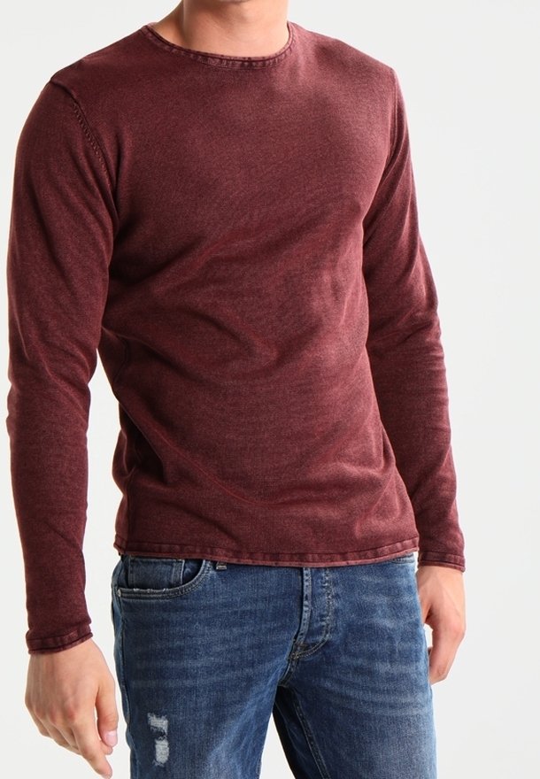 Chemise bordeaux à manches longues en tissu doux, avec un col rond et des coutures simples, associée à un jean bleu déchiré.