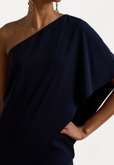 Robe asymétrique bleu marine avec un design à une épaule ; fabriquée dans un tissu lisse, présentant une texture drapée et une coupe décontractée.