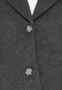 Manteau en mélange de laine gris foncé avec un col classique, deux boutons en argent en forme de rose, et une finition en tissu doux et texturé.