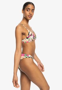 Blommig bikinitrosa som har en triangelöverdel med tunna remmar och låg midja, båda i svarta, rosa och gröna nyanser med tropiska mönster.