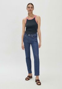 Zwarte tanktop met roze rand, gecombineerd met strakke donkerblauwe jeans en bruine blokhak sandalen. Eenvoudig ontwerp, gladde textuur.