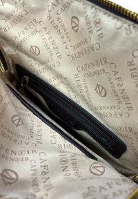 Interno marrone di una borsa, con una tasca con zip e un motivo ripetuto del logo "Cafè Noir". Tessuto liscio con zip dorata.