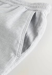 Light gray fabric waistband with elasticated texture, featuring stitched seams and side openings for comfort and ease of wear.