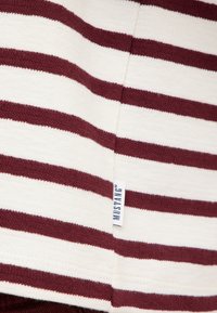 Gestreifter Strickpullover in Weiß und Burgunderrot, mit einer strukturierten Stoffoptik und einem kleinen Logoband am Saum.