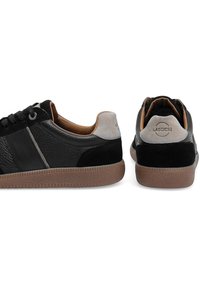 Madalõhised mustad nahast spordijalatsid pruunide tallade, hallide nubukist kontsapakkide ja mustade paeltega; üks king näitab külgvaadet, teine tagavaadet.