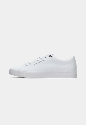 Low-top white sneaker with white laces, flat sole, and Tommy Hilfiger logo on side and near the top eyelet.