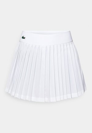 Falda blanca con pliegues y una amplia cinturilla elástica. Presenta un logo en verde y rojo en la parte delantera, fabricada con una tela ligera.