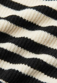 Tessuto a righe nere e crema con superficie strutturata a coste. Le righe si alternano in un motivo ondulato, creando profondità visiva e contrasto.