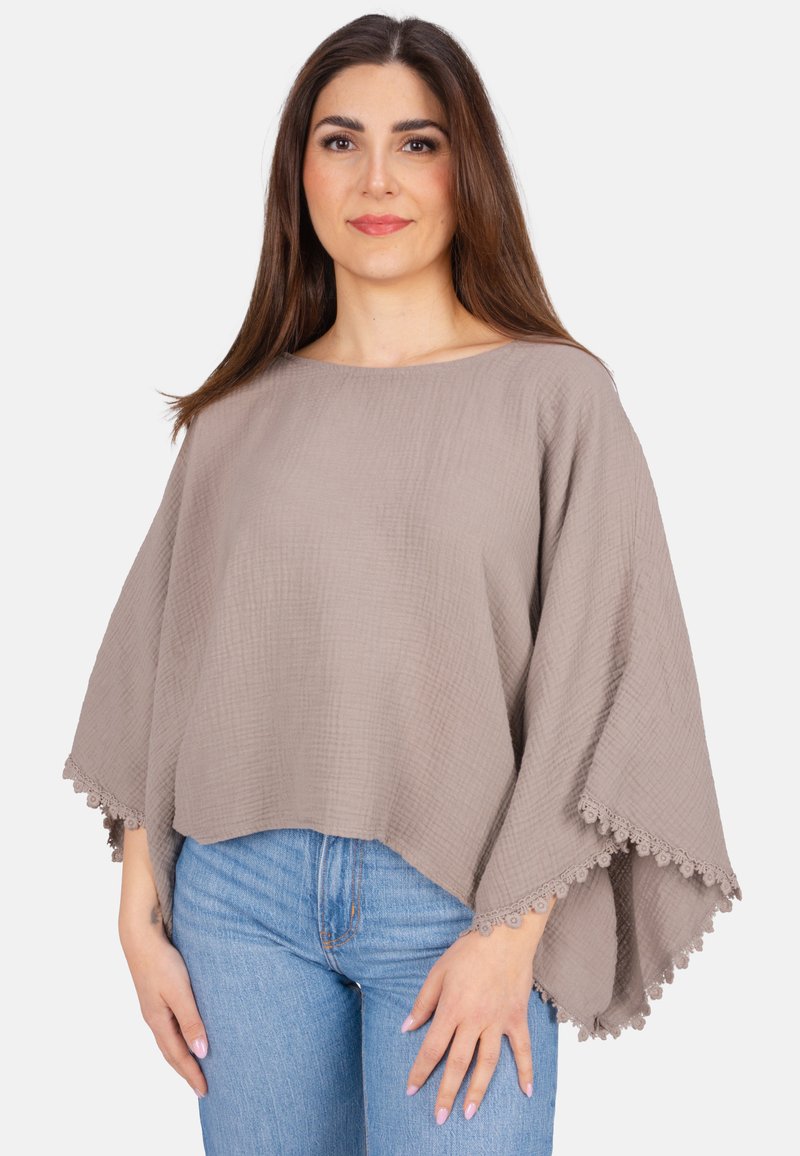 Hellbraunes, strukturiertes Oberteil mit weitem Ausschnitt und lockerer Passform. Verfügt über eine gewellte Spitzenverzierung am Saum. Kombiniert mit blauen Jeans.