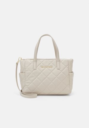 Beige quilted handbag with dual top handles, side pockets, detachable strap, and gold "Valentino" logo on front center.