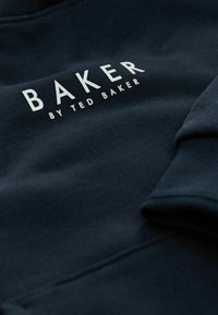Felpa blu navy realizzata in tessuto morbido, con la scritta "BAKER by TED BAKER" in bianco. Include polsini a costine con dettagli di cucitura.